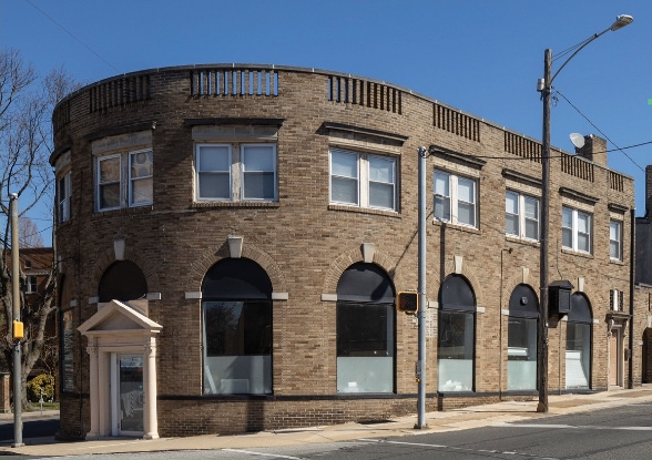 A curved two-story brick building with arched windows and a storefront.